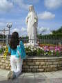 A pilgrim in prayer before the Statue of Queen of Peace